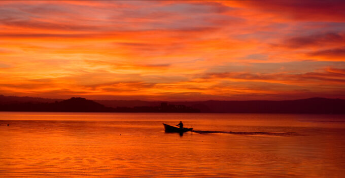fisherman sets nets on lake Bolsena sunset